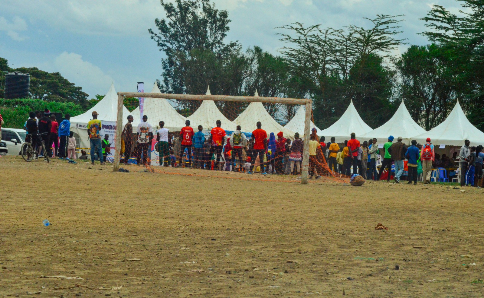 Community members gathered beside a football goal at an outreach event